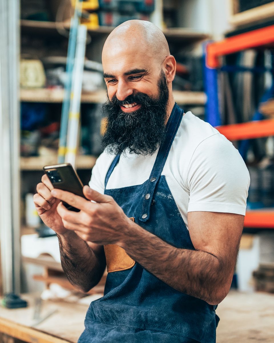 A woodworker in his workshop, reading the details on his phone
